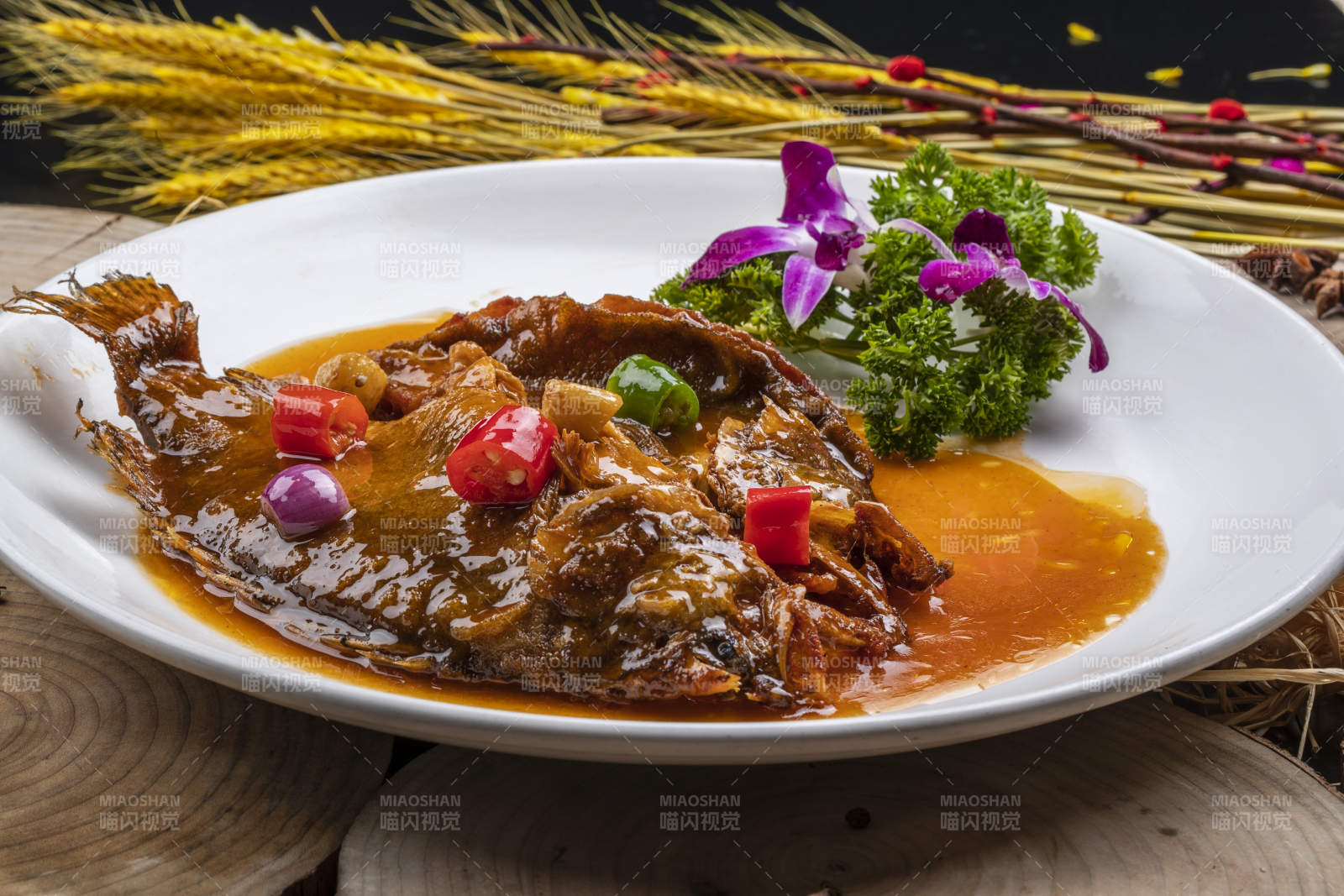 白色圓盤裝的紅燒羅非魚擺放在樟木砧板上