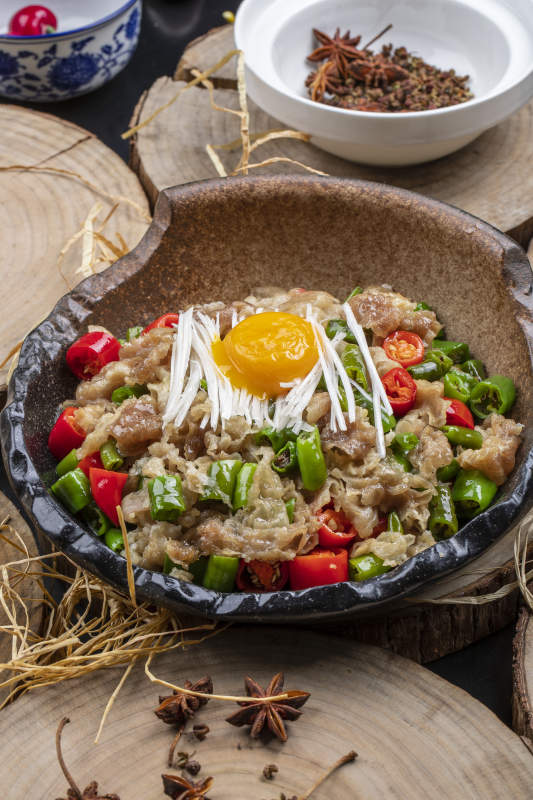 陶盘装的小米辣炒肥牛摆放在樟木砧板上