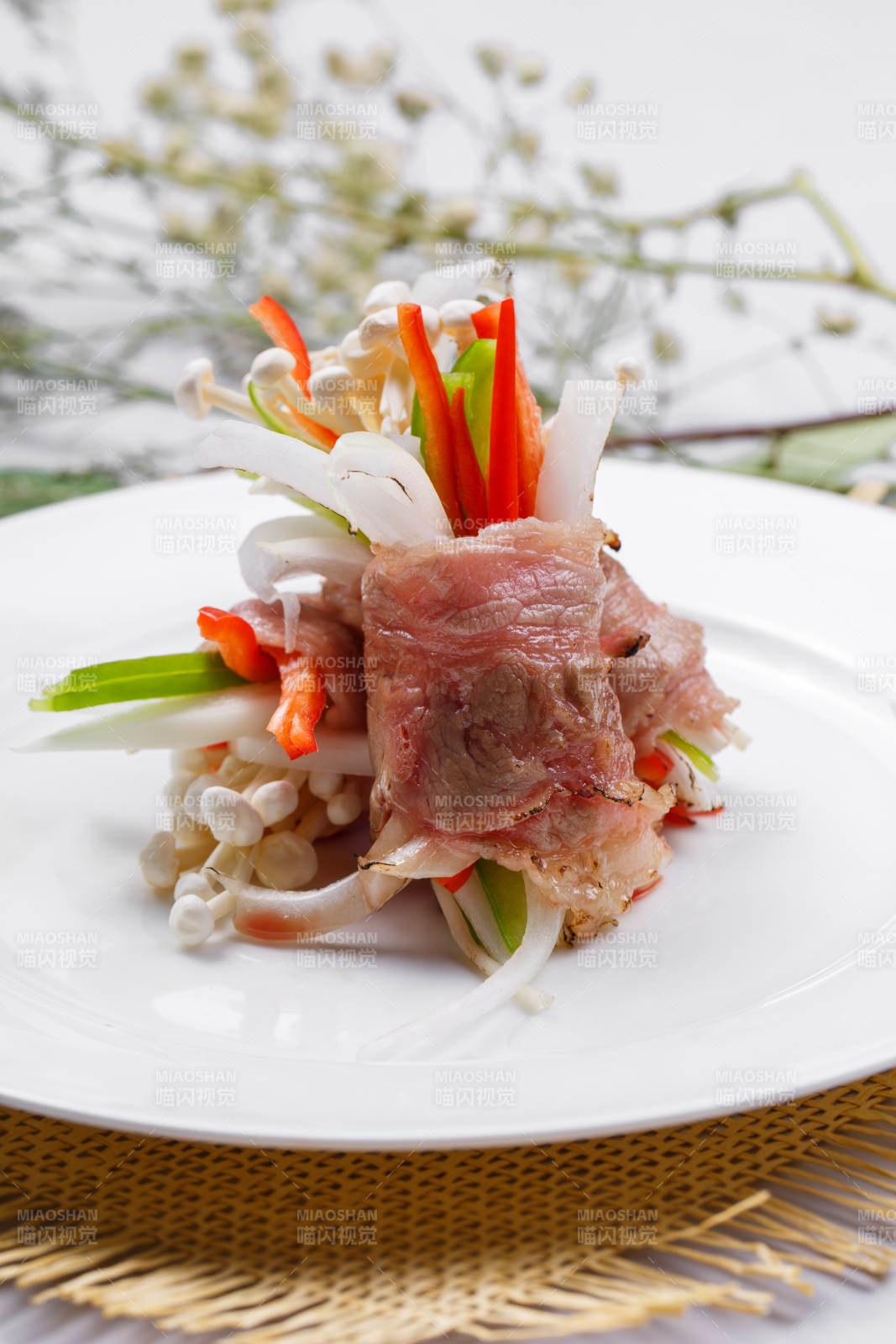 白色圆盘装的法式鹅肝牛肉卷摆放在草垫上