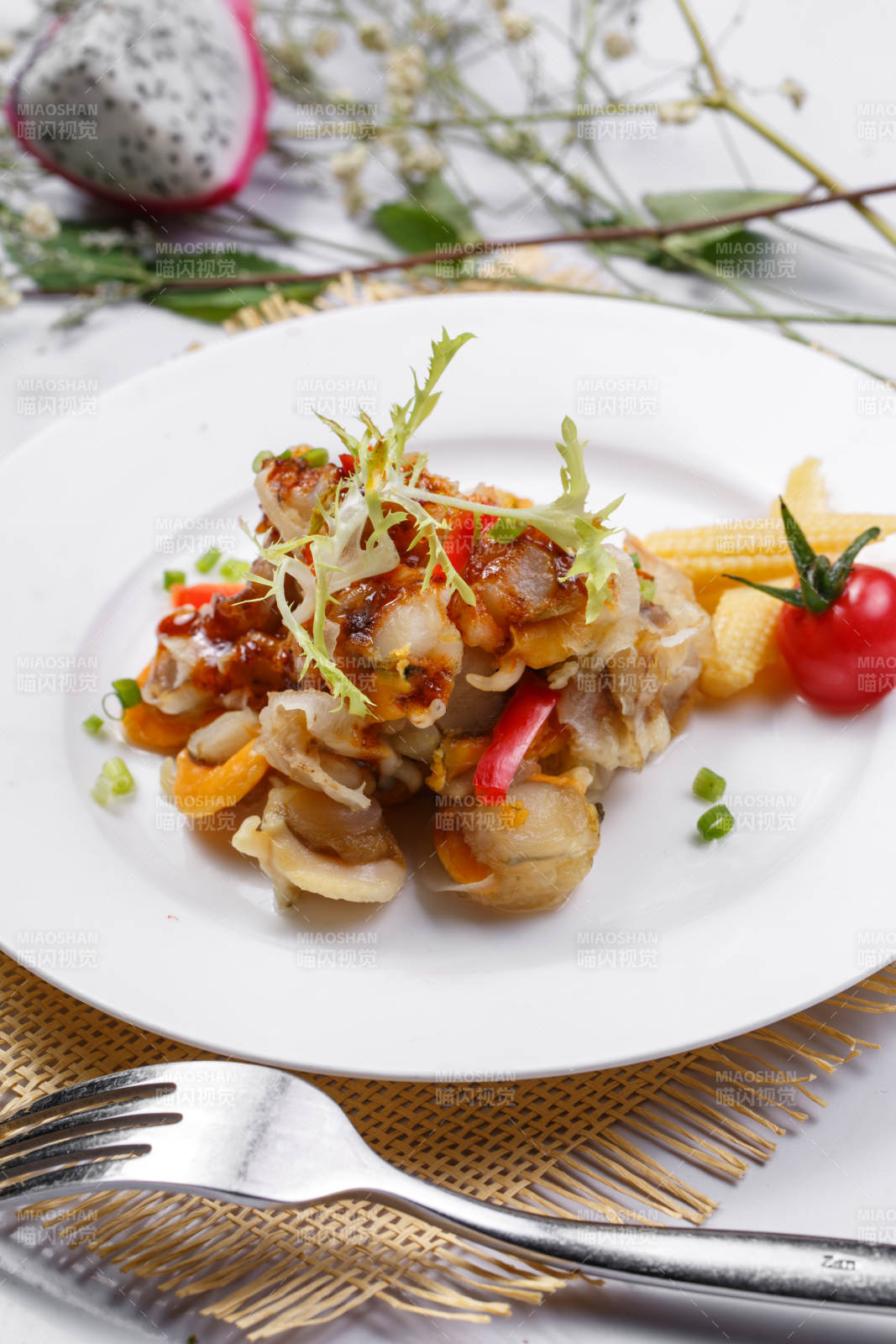 白色瓷盘装的铁板香辣扇贝肉摆放在草垫上