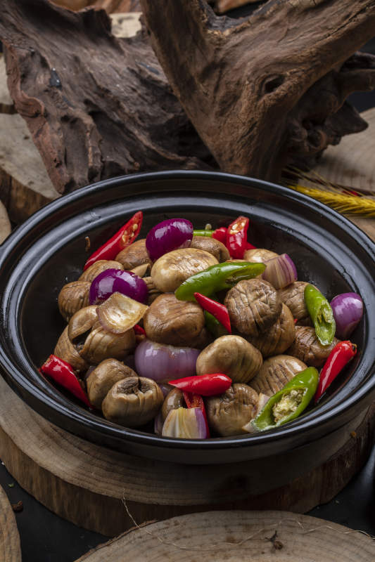 黑色砂锅装的小葱头鲜口蘑米椒煲