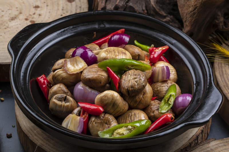 黑色砂锅装的小葱头鲜口蘑米椒煲