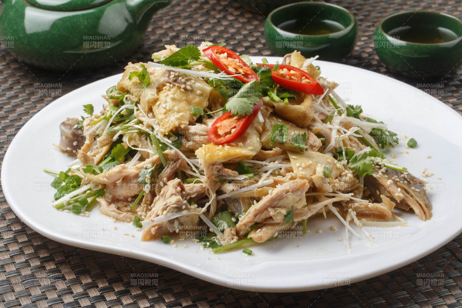 扇形白瓷盘装的麻辣手撕鸡摆放在餐垫上