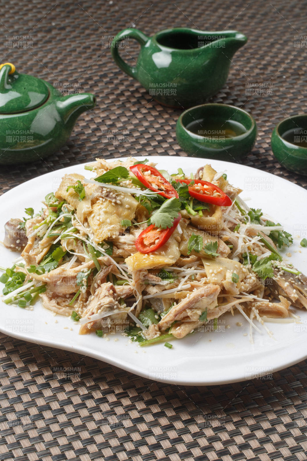 扇形白瓷盘装的麻辣手撕鸡摆放在餐垫上