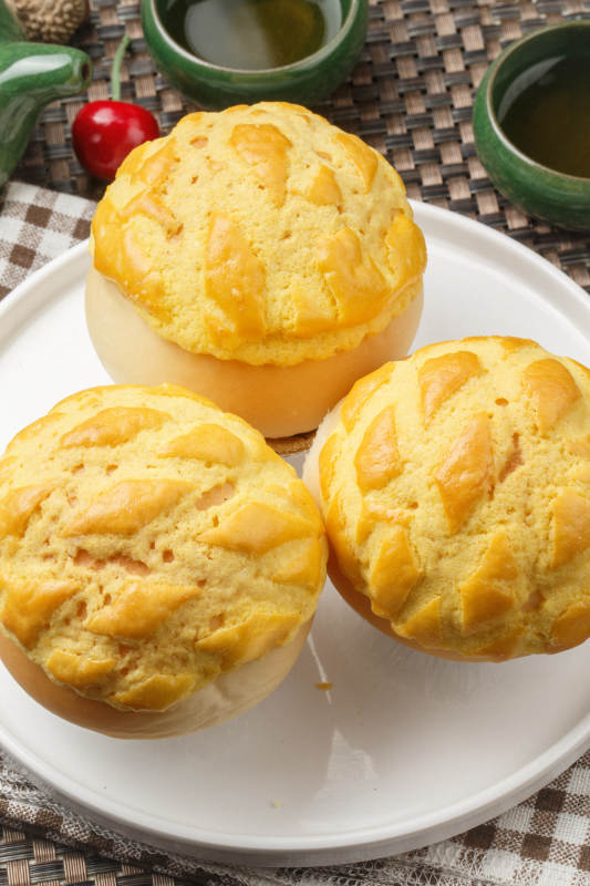 圆形白瓷盘装的酥皮菠萝包摆放在餐垫上