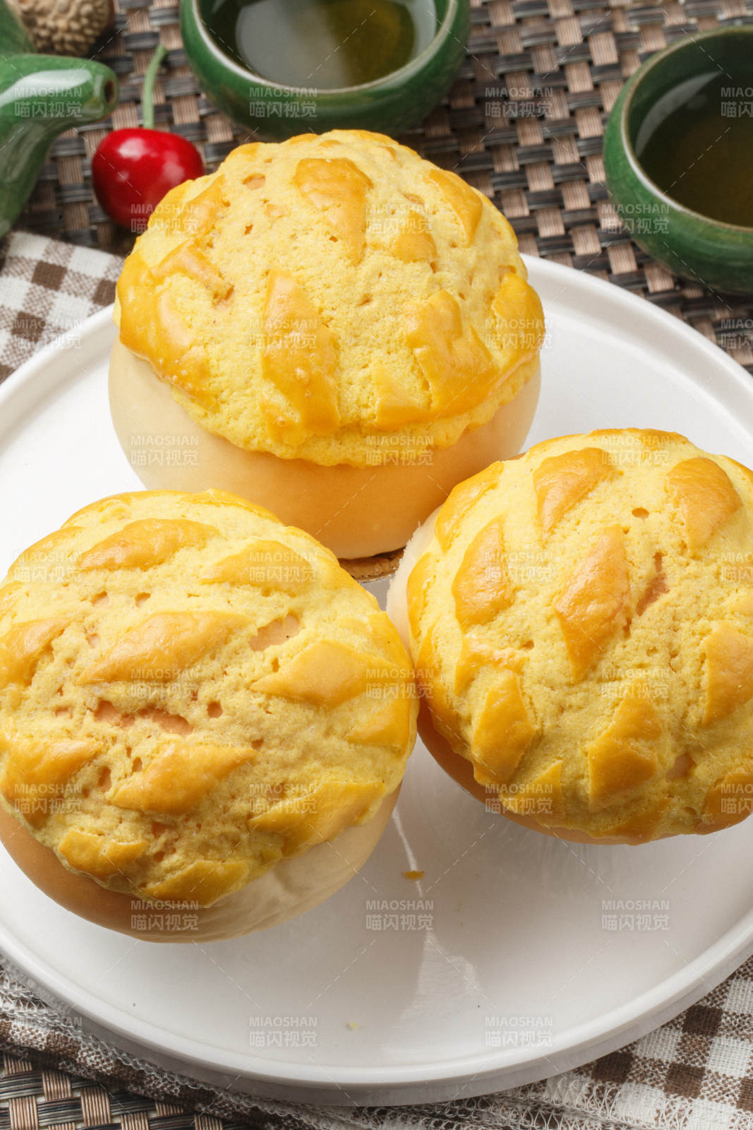 圆形白瓷盘装的酥皮菠萝包摆放在餐垫上