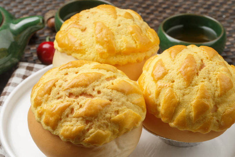 圆形白瓷盘装的酥皮菠萝包摆放在餐垫上