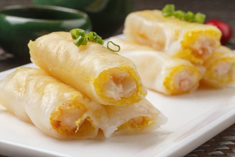 长方形白瓷盘装的虾仁肠粉摆放在餐垫上