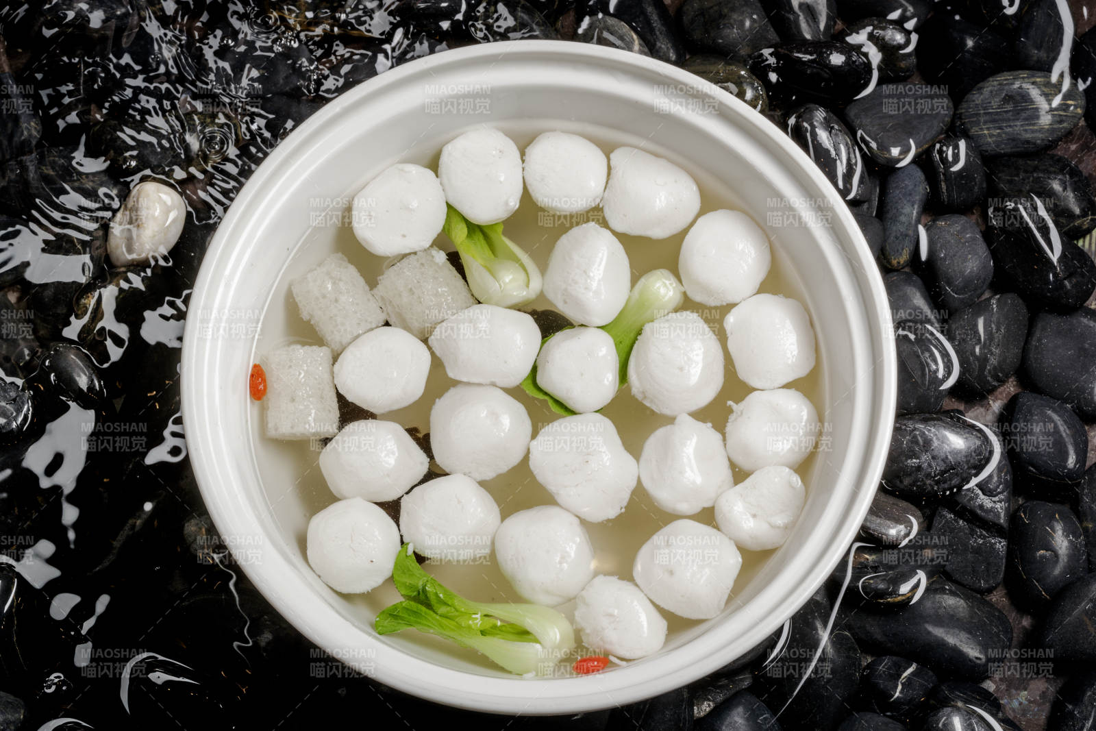 西湖鱼圆摆放在布满黑色鹅卵石的水中