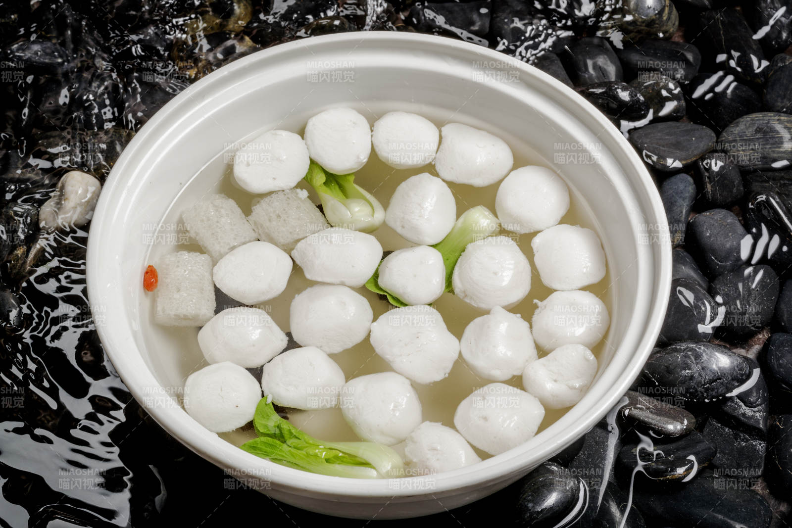 西湖鱼圆摆放在布满黑色鹅卵石的水中