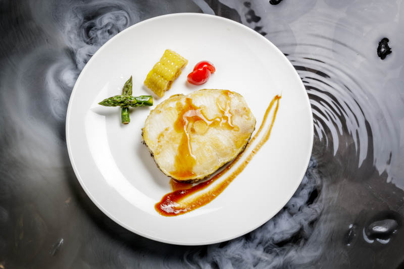 香煎银鳕鱼摆放在干冰缭绕的水中