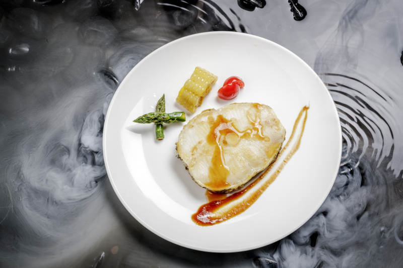 香煎银鳕鱼摆放在干冰缭绕的水中