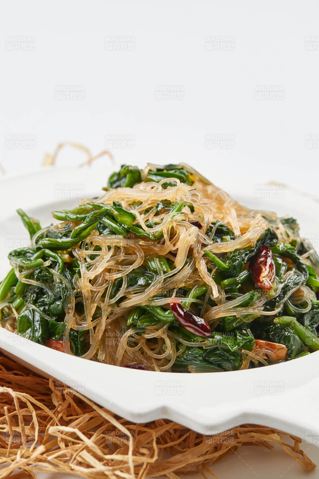 白色瓷盘装的凉拌粉丝菠菜