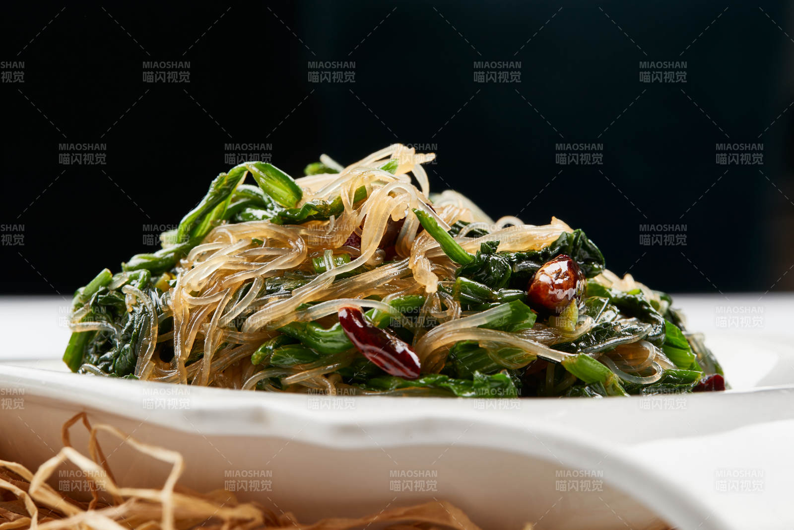 白色瓷盘装的凉拌粉丝菠菜