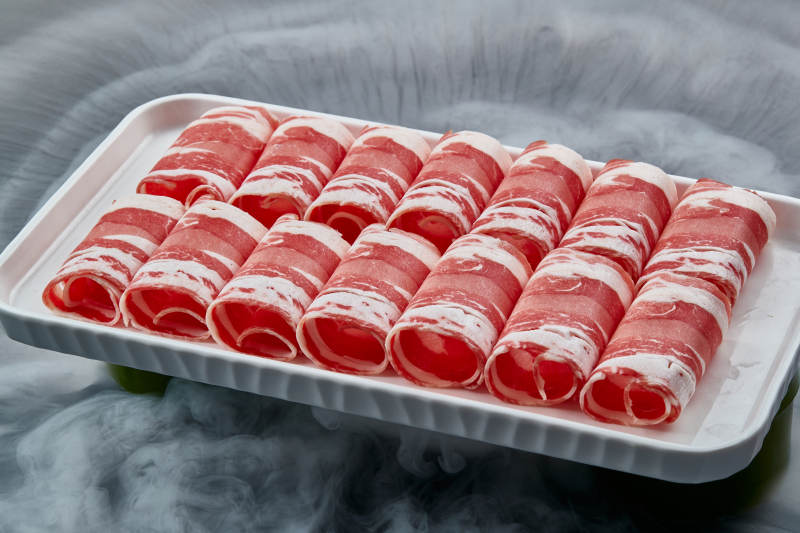 干冰缭绕的背景上摆放的草原肥羊肉卷