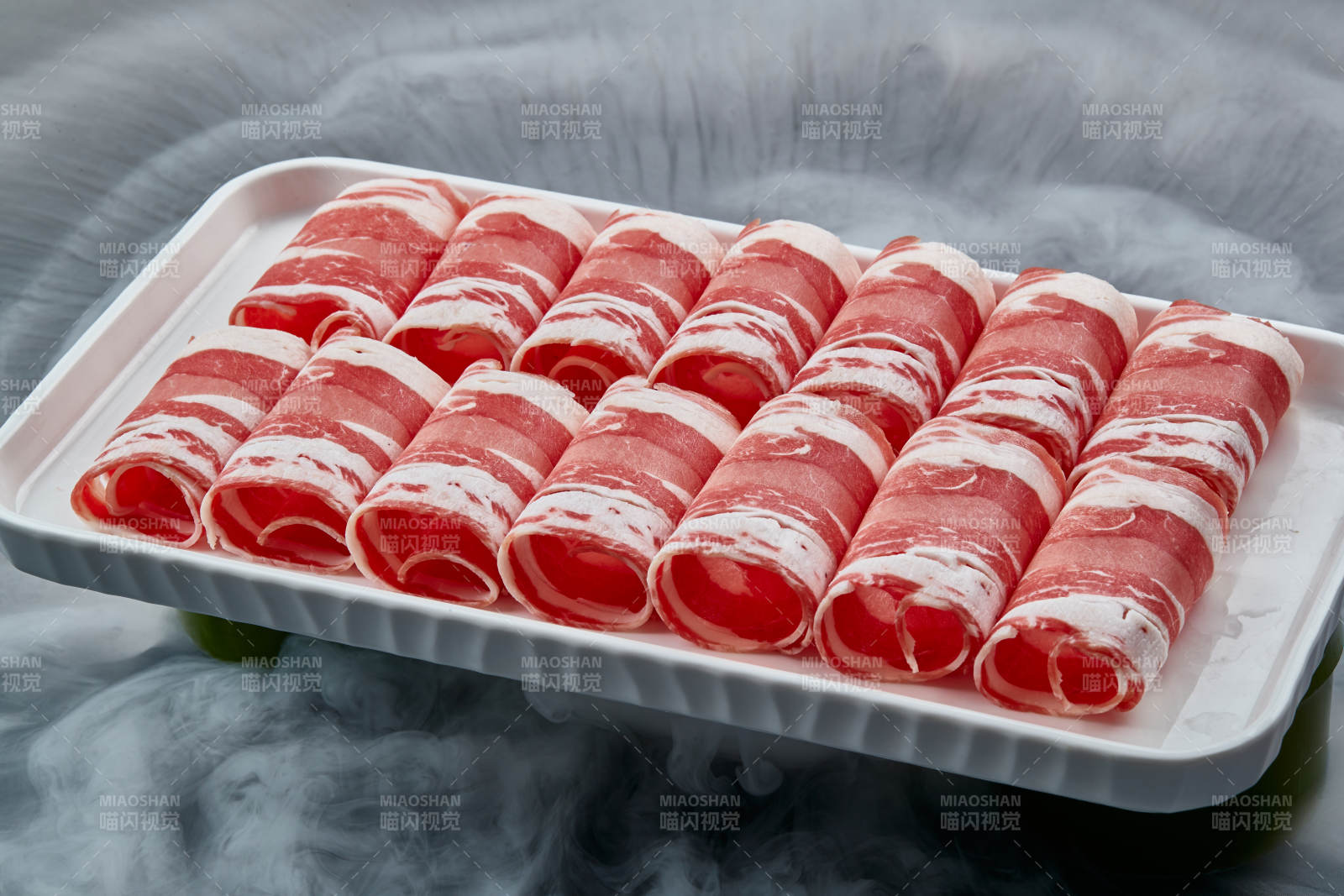 干冰缭绕的背景上摆放的草原肥羊肉卷