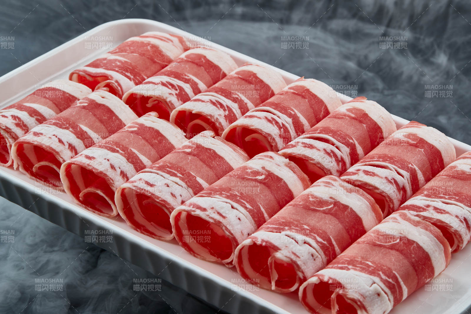 干冰缭绕的背景上摆放的草原肥羊肉卷