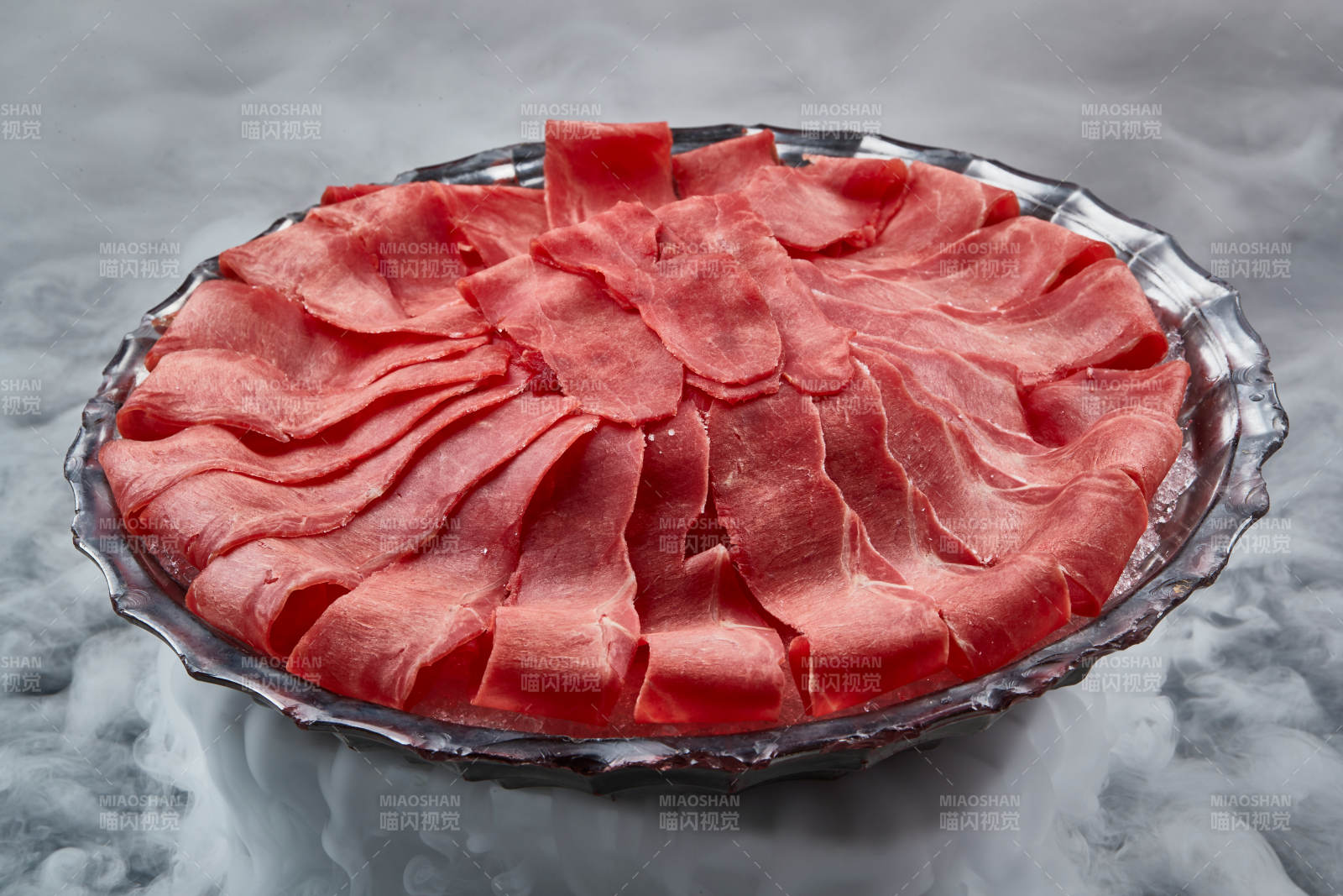 干冰缭绕的背景上摆放的鲜牛肉刺身