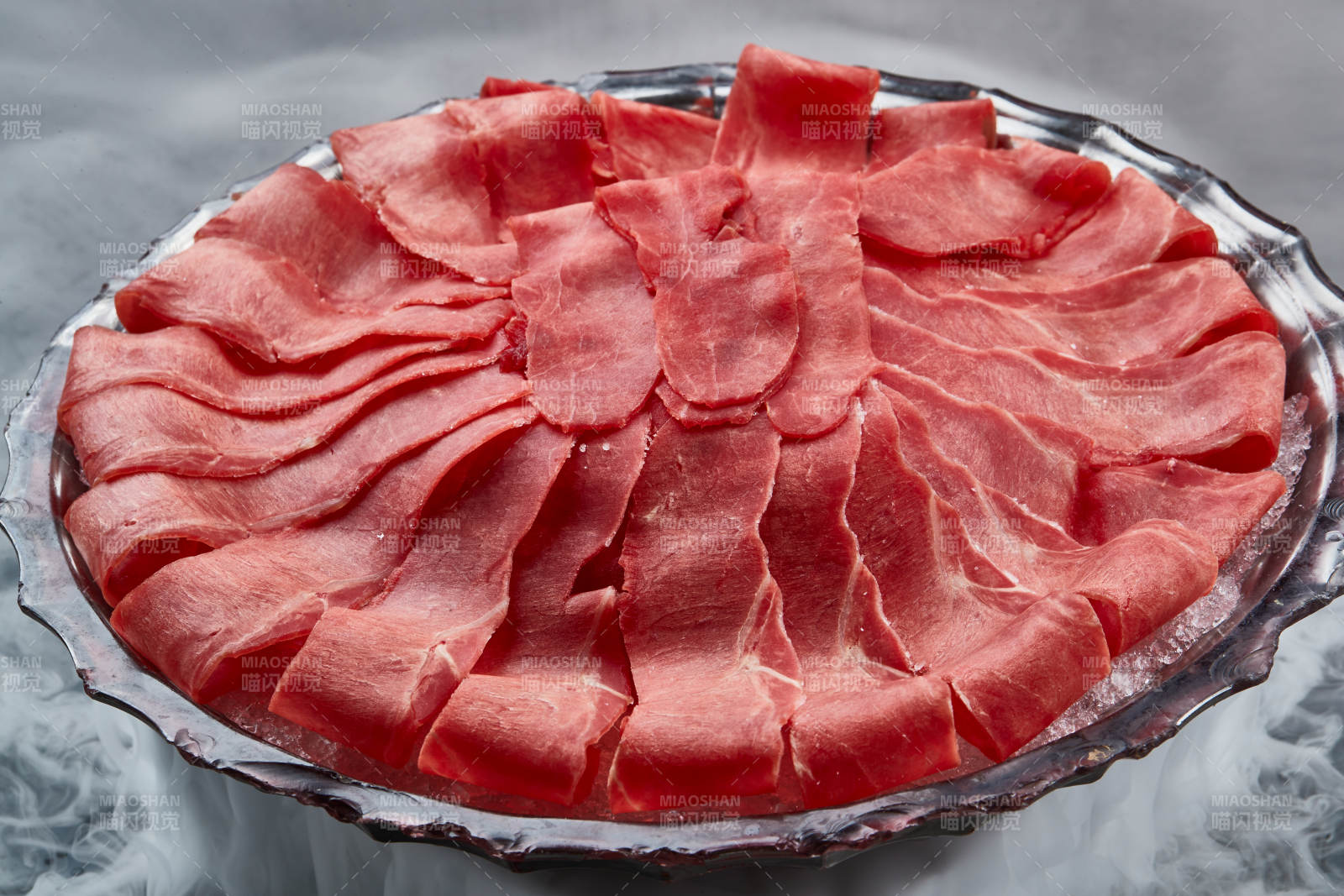 干冰缭绕的背景上摆放的鲜牛肉刺身