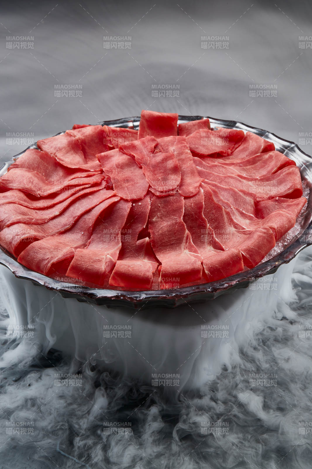 干冰缭绕的背景上摆放的鲜牛肉刺身