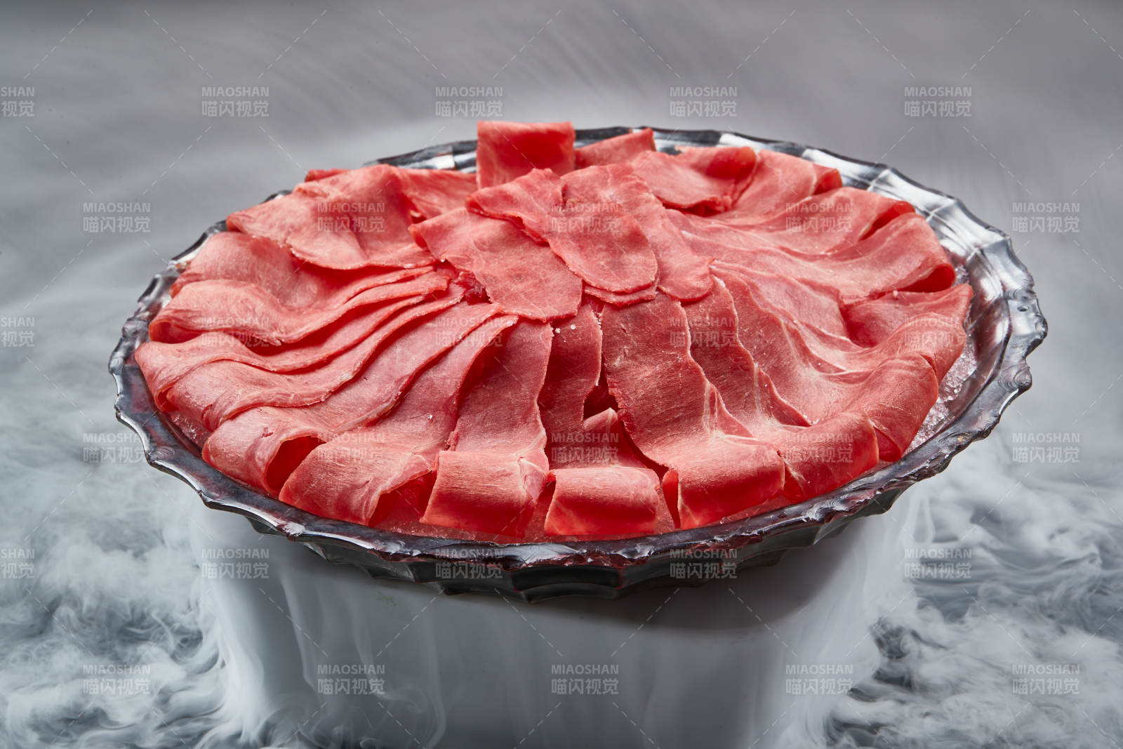 干冰缭绕的背景上摆放的鲜牛肉刺身