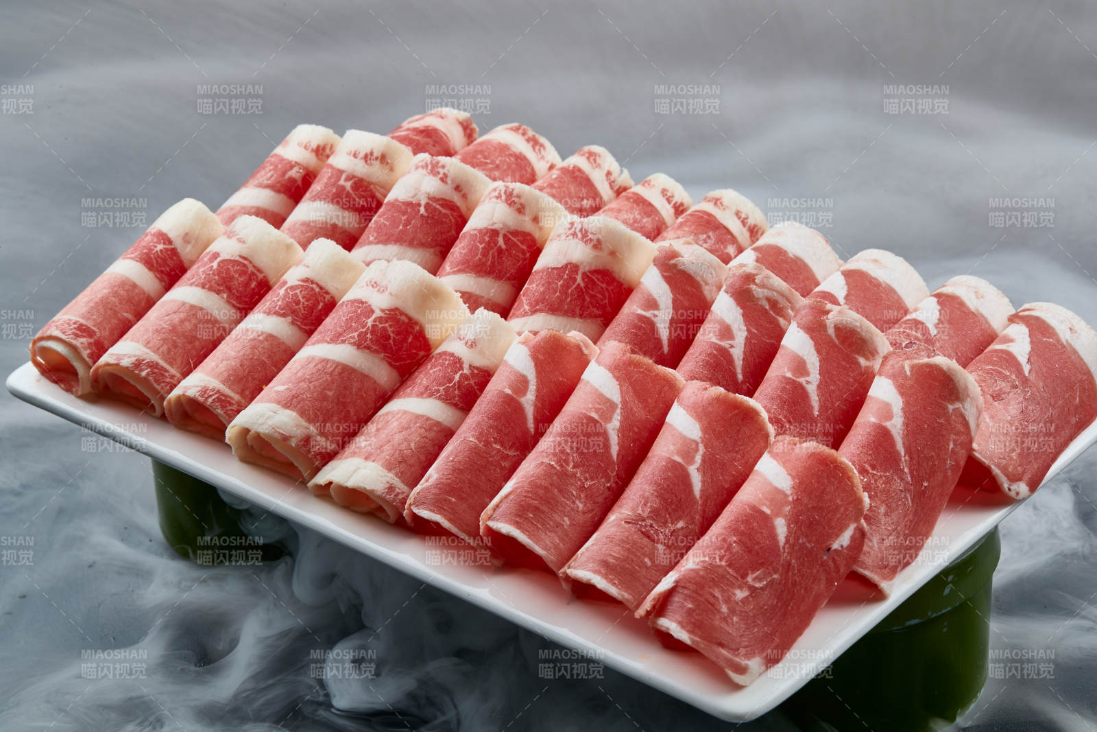 干冰缭绕的背景上摆放的牛羊肉卷双拼