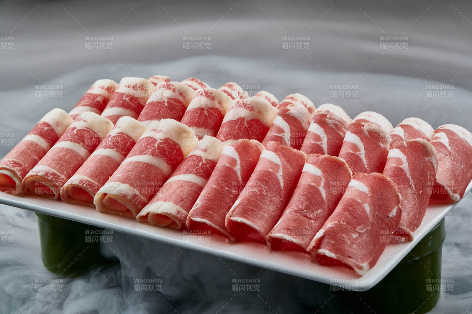 干冰缭绕的背景上摆放的牛羊肉卷双拼