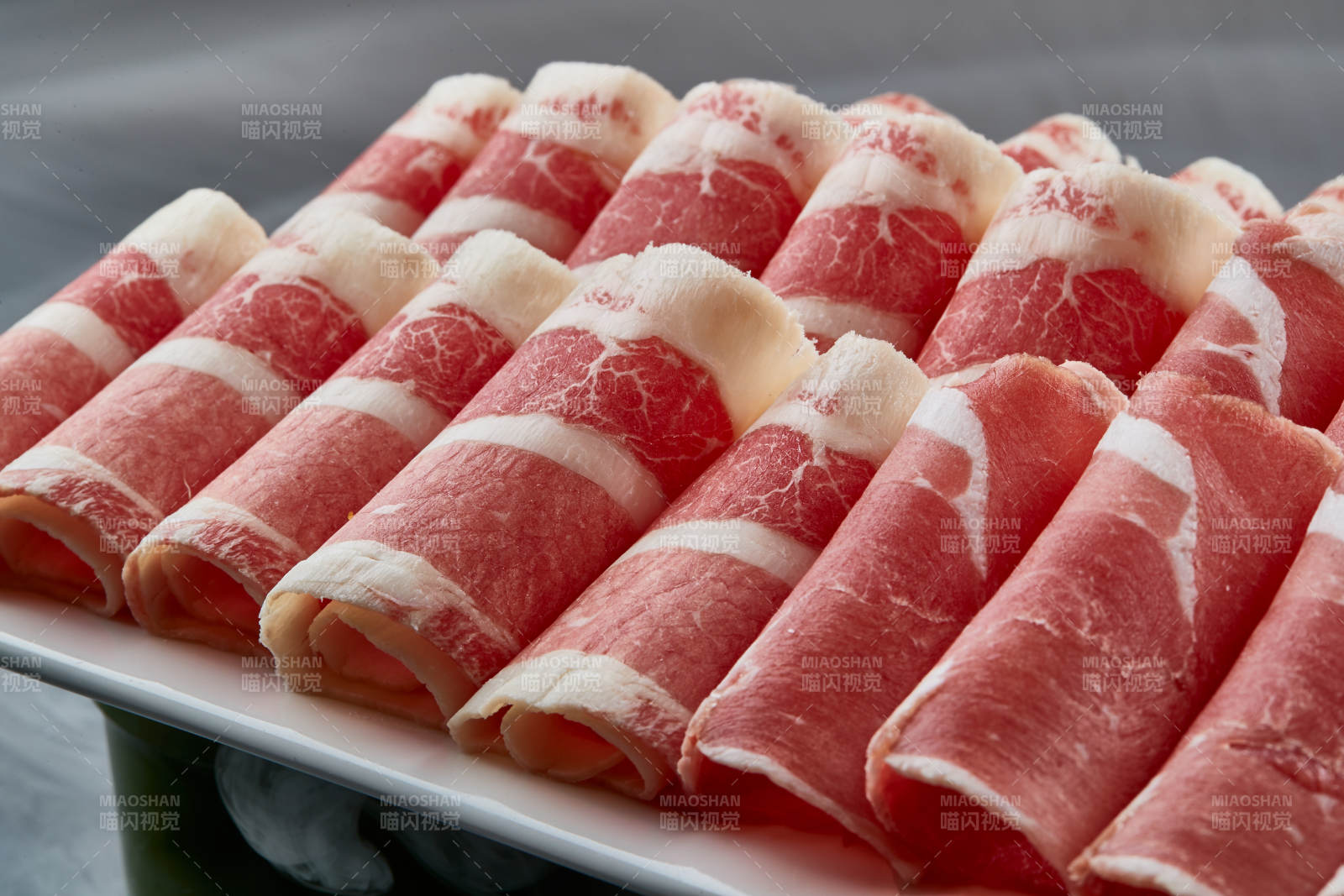 干冰缭绕的背景上摆放的牛羊肉卷双拼