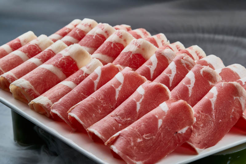 干冰缭绕的背景上摆放的牛羊肉卷双拼