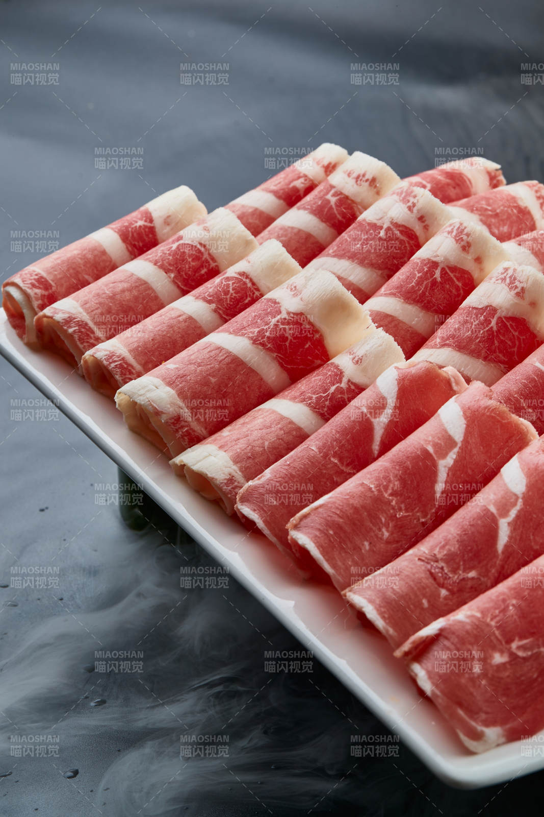 干冰缭绕的背景上摆放的牛羊肉卷双拼