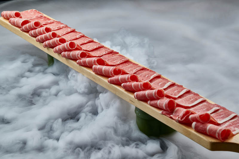 干冰缭绕的背景上摆放的和牛一米肉片