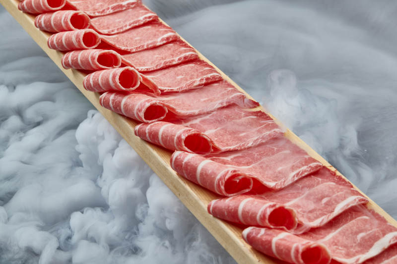 干冰缭绕的背景上摆放的和牛一米肉片