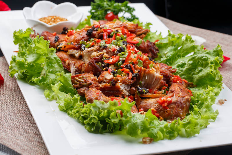 陈旧木板上的方瓷盘装的风味手撕兔