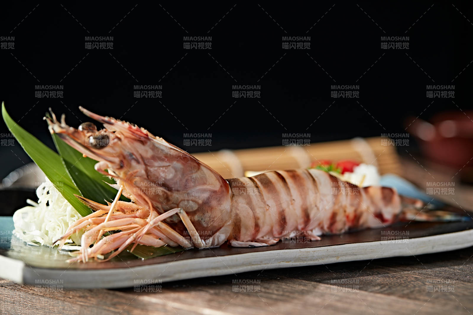 长方形瓷盘装的铁板野生明虾皇摆放在草垫上