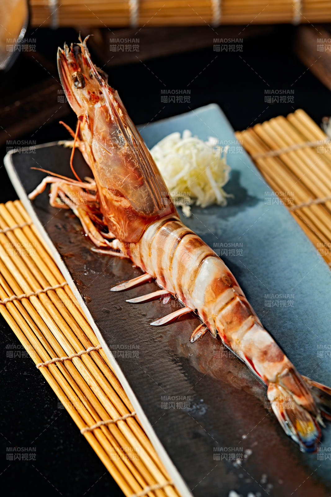 長方形瓷盤裝的鐵板野生明蝦皇擺放在草墊上圖片