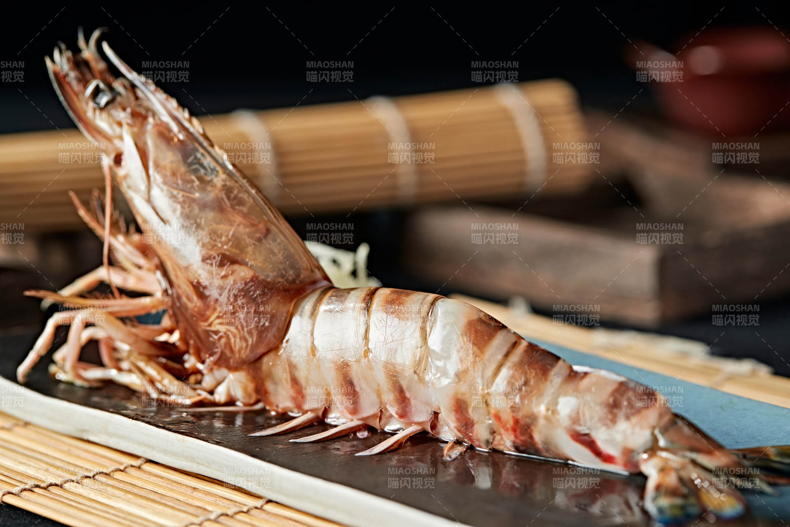 长方形瓷盘装的铁板野生明虾皇摆放在草垫上