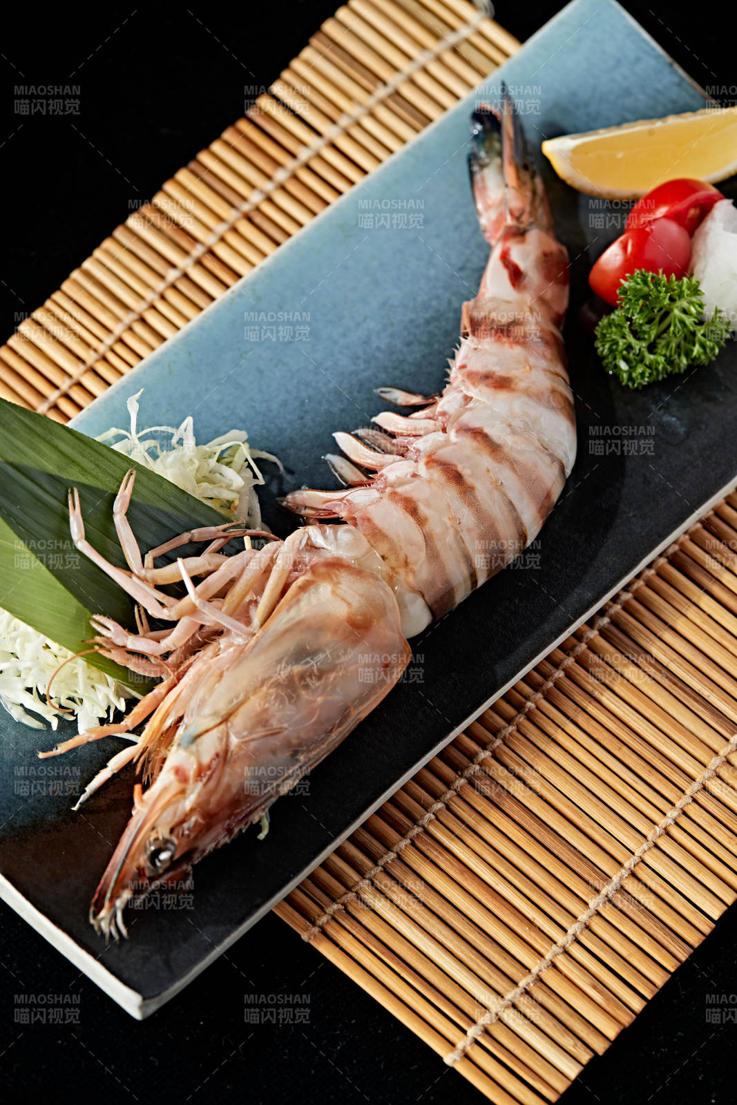 長方形瓷盤裝的鐵板野生明蝦皇擺放在草墊上