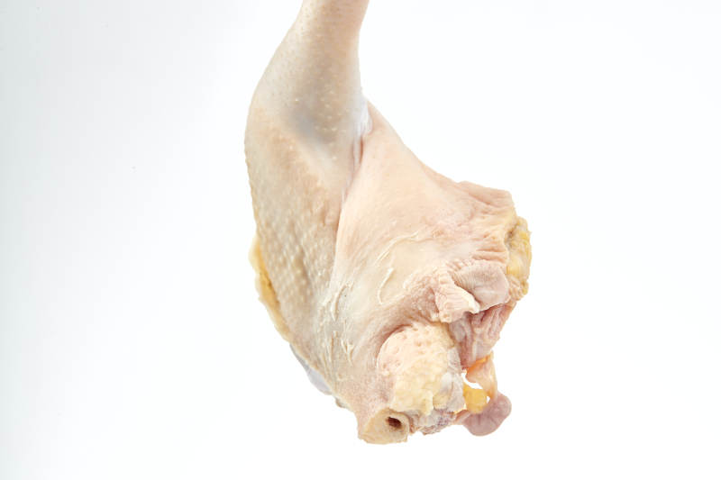 摆放在白色背景上分切好的生鲜鸡腿