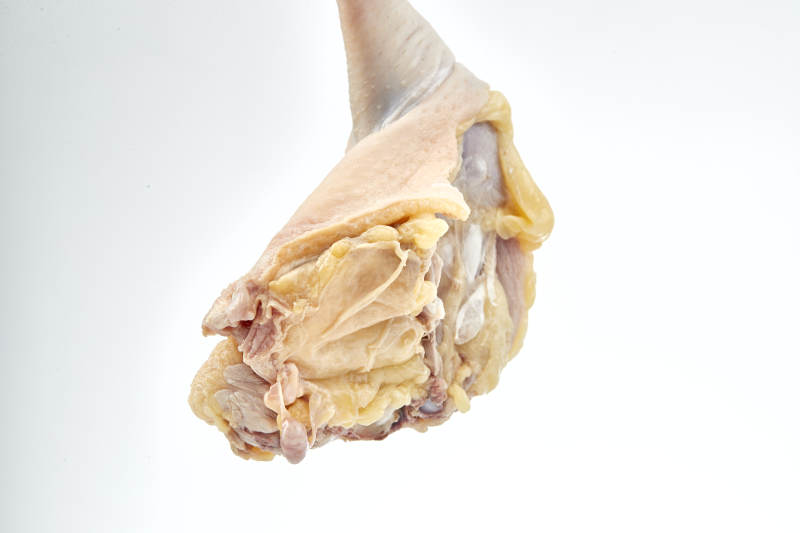 摆放在白色背景上分切好的生鲜鸡腿