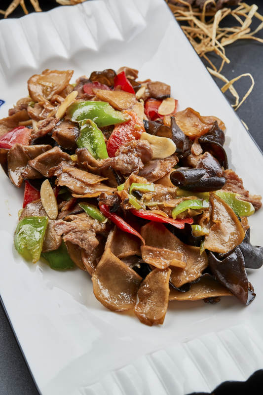 白色瓷盘装的肉炒山珍杂菌