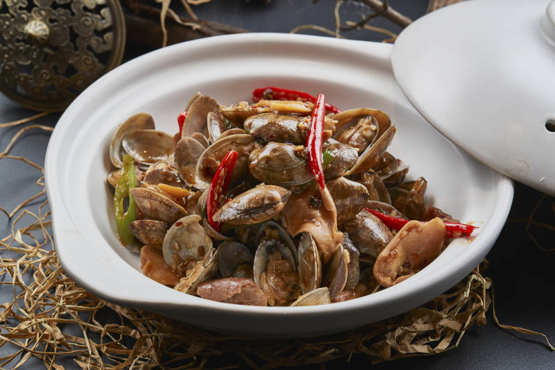 白色砂锅装的辣椒煲花蛤