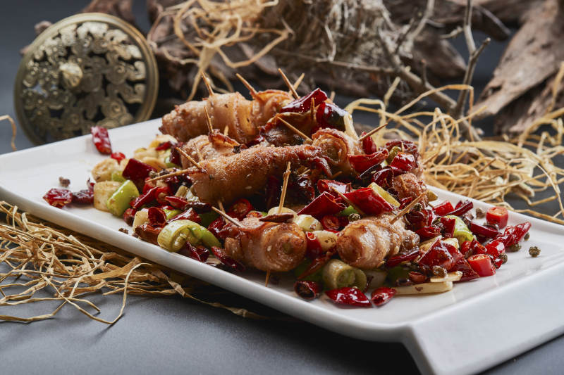 白瓷盘装的辣子油炸五花肉山椒卷