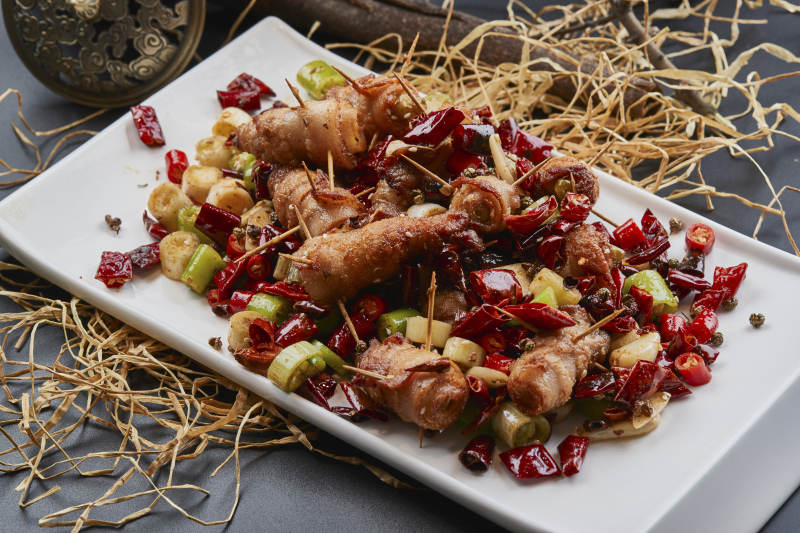 白瓷盘装的辣子油炸五花肉山椒卷