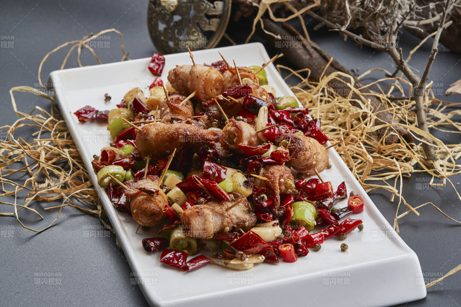 白瓷盤(pán)裝的辣子油炸五花肉山椒卷