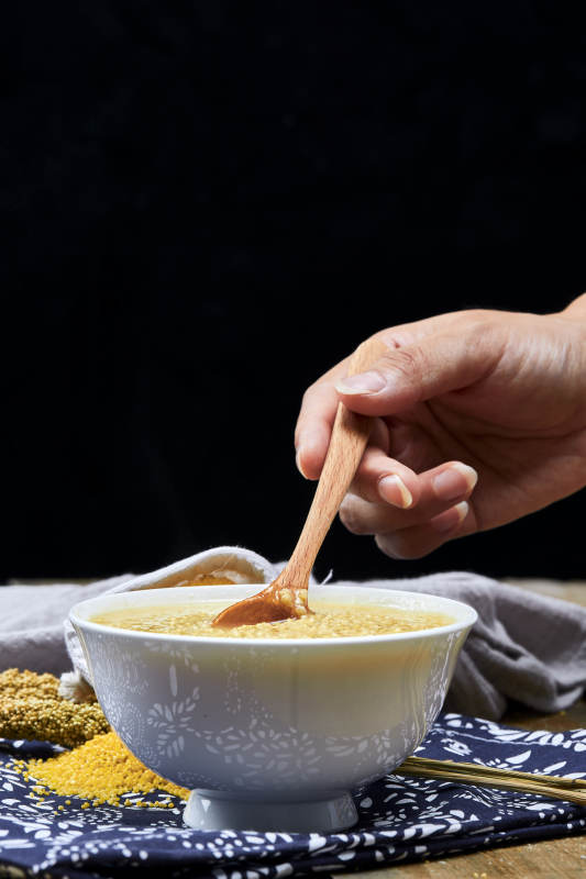 手持木勺㧟起的美味香浓小米粥