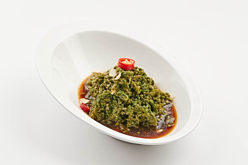 白色瓷盘装的醋腌凉拌木瓜花