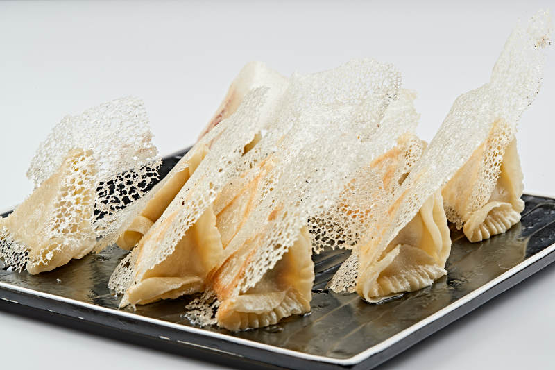 黑色瓷盘装的渔网水煎包