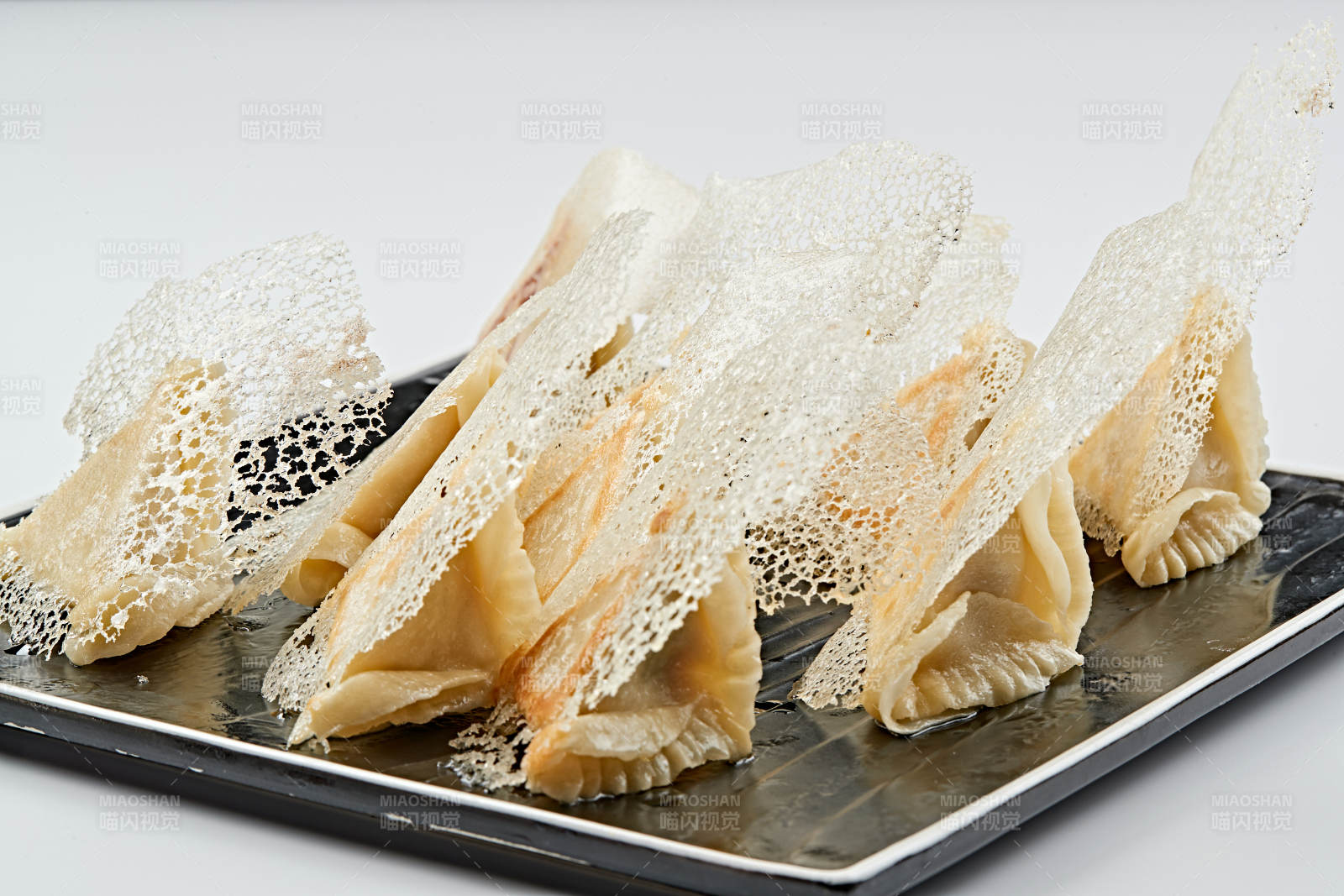 黑色瓷盘装的渔网水煎包