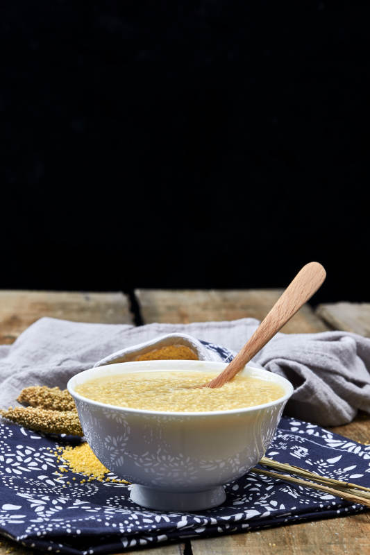 手持木勺㧟起的美味香浓小米粥