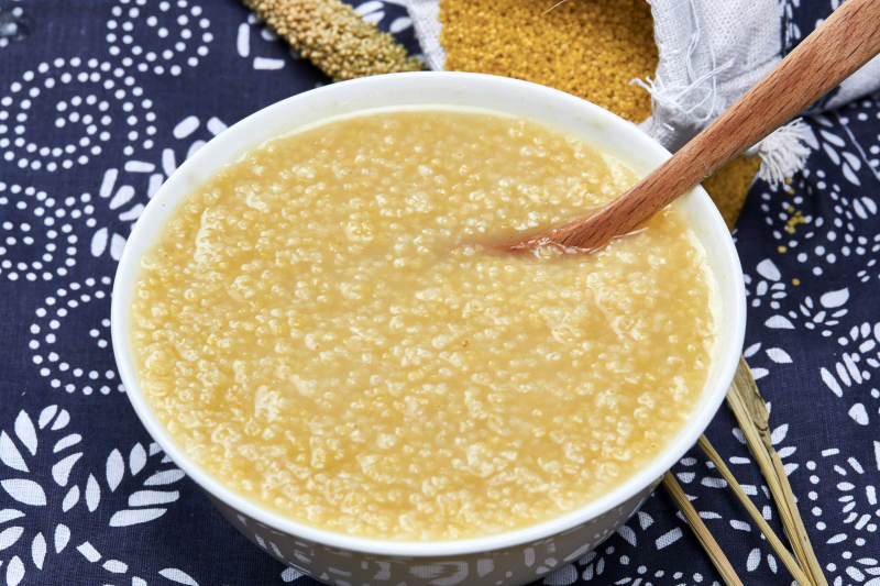 手持木勺㧟起的美味香浓小米粥